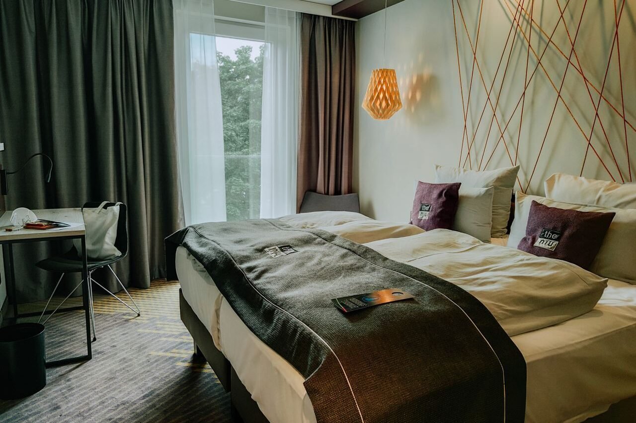 A modern and cozy hotel room featuring a double bed, stylish lighting, and a workspace.